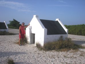 Brian stands in
        front of a typical Slave Hut in Bonnaire