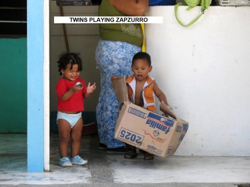Twins playing in a
        card board box in the Square Zapzurro